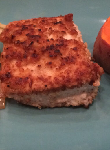 A blue plate with macadamia nut crusted mahi mahi, peppers and a sweet potato on it.
