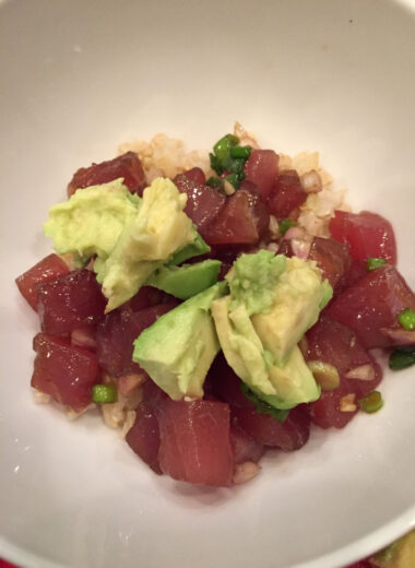 A bowl with rice, ahi poke and avocado inside.