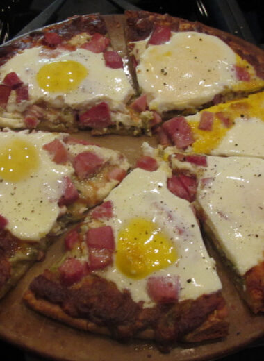 a gluten free pizza topped with eggs, ham and cheese.