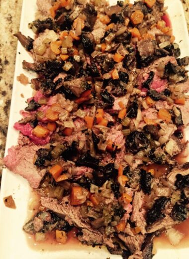A plate with medium rare pressure cooker tri tip on it with mushrooms and carrots.
