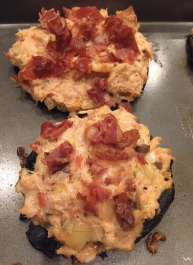 Two large mushrooms filled with crab stuffing and topped with crispy prosciutto.