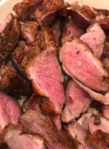 A platter full of sliced seared duck breasts.