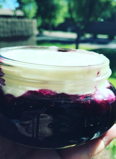 A jar filled with blueberry sauce and home made yogurt.