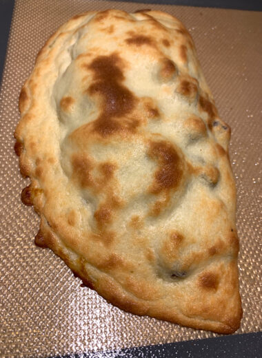 A calzone sitting on a baking mat.