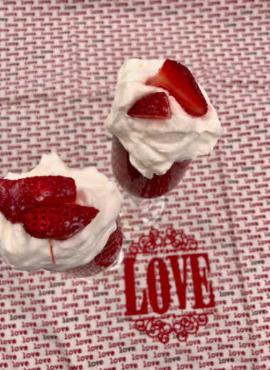 A red and white background with the word love written on it and two champagne glasses filled with chocolate and strawberries in them.