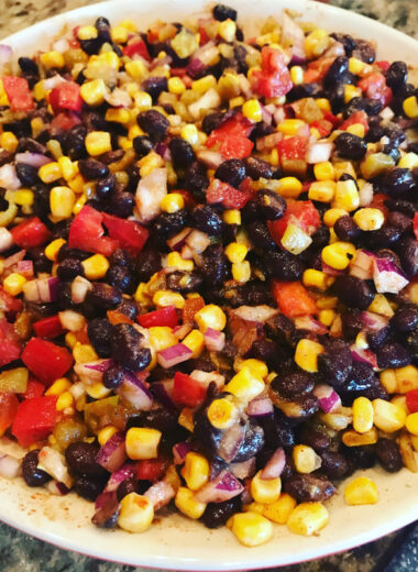 A bowl full of corn, black beans, pinto beans, tomatoes, peppers and cilantro.