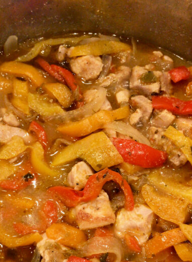 An instant pot filled with chicken, red and yellow peppers and onions with spices.