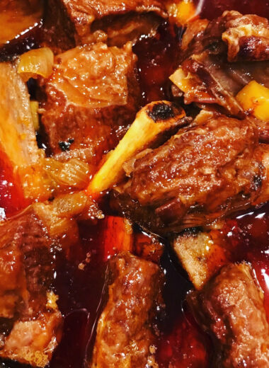 A pan full of ribs in a sweet and sour sauce.
