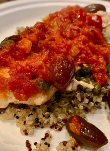 A plate with fish, quinoa, red sauce and veggies on it.