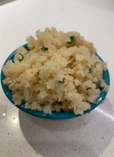 A blue bowl of cauliflower rice with seasonings in it.