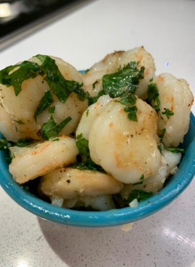 A blue bowl full on shrimp with seasoning on it.