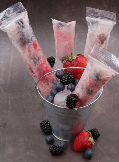 A metal bucket with berries in it and frozen berries in popsicle containers with prosecco in them.