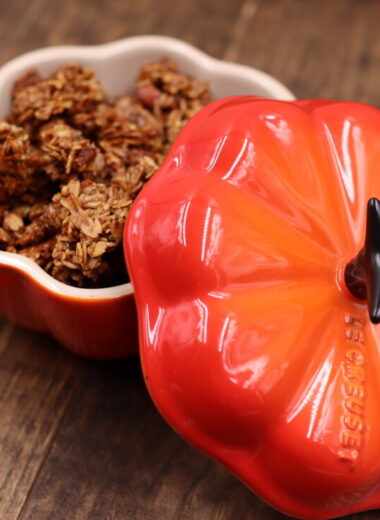 A pumpkin shaped dish that is holding brown granola.