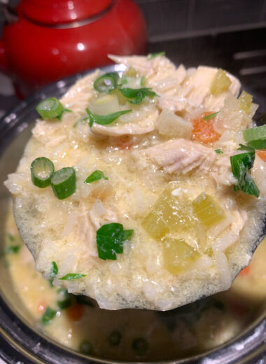 A ladle full of chicken and rice soup.