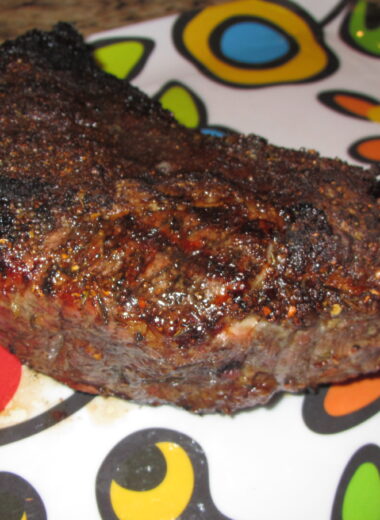 A tri tip rubbed with Jamaican Jerk seasoning sitting on a colorful platter.