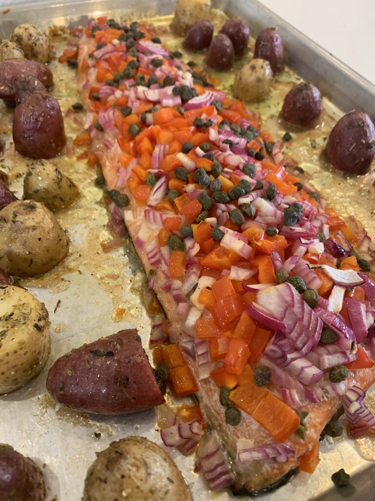 A sheet pan with roasted potatoes and salmon on it.