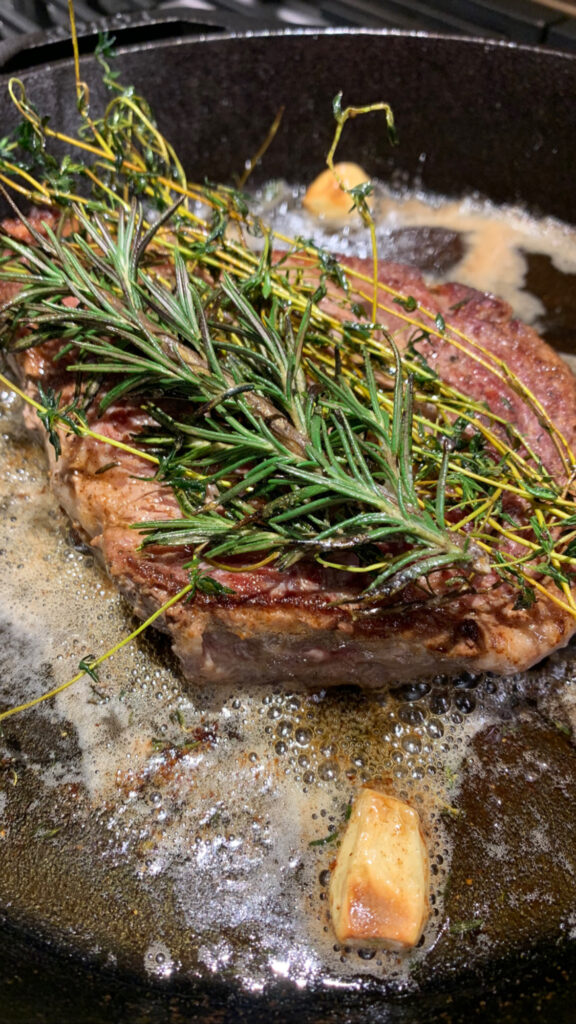 Seared steak with rosemary on top and butter around it